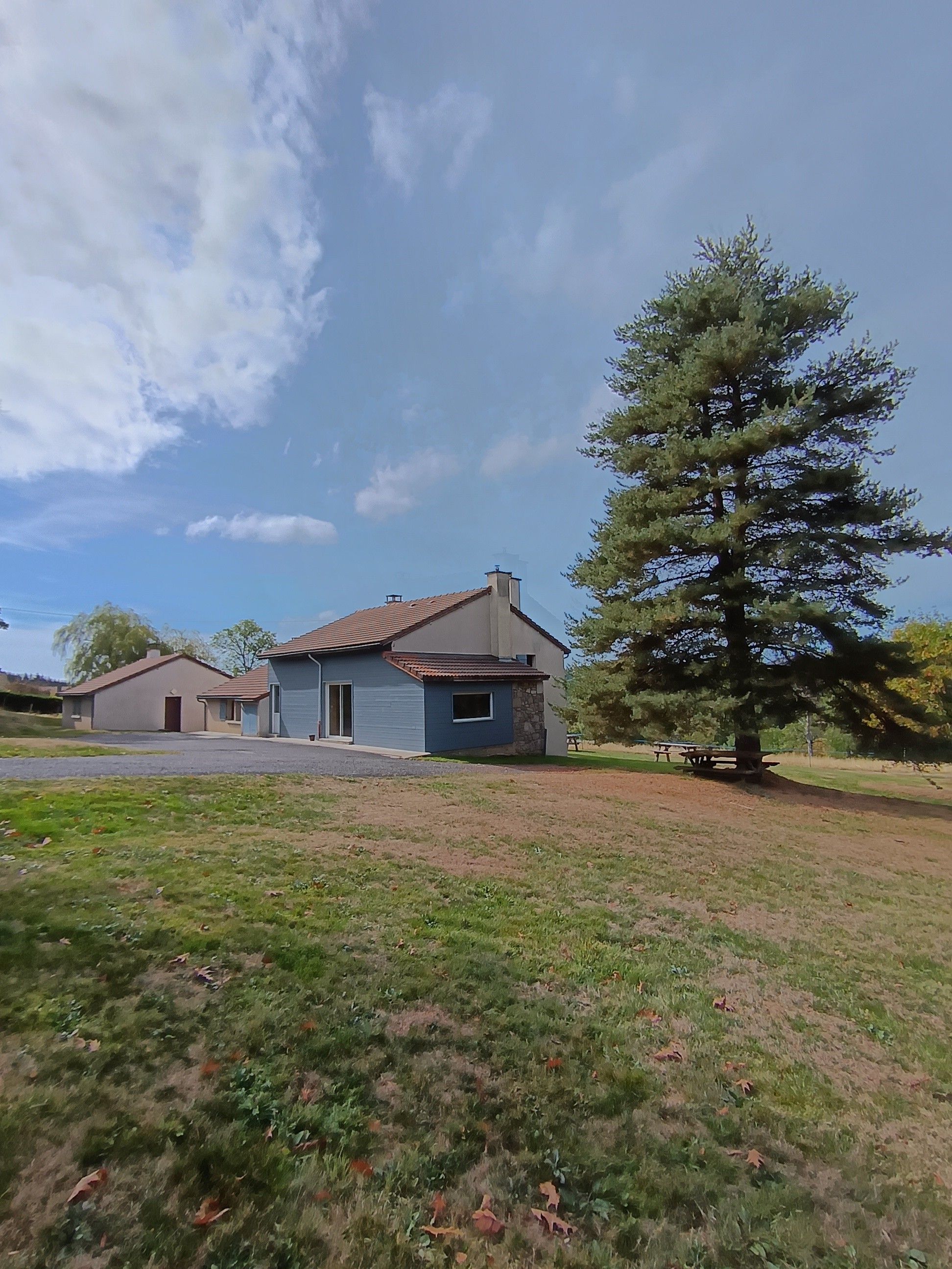 A residential property with a two-story house, a driveway, and a large tree in the front yard.