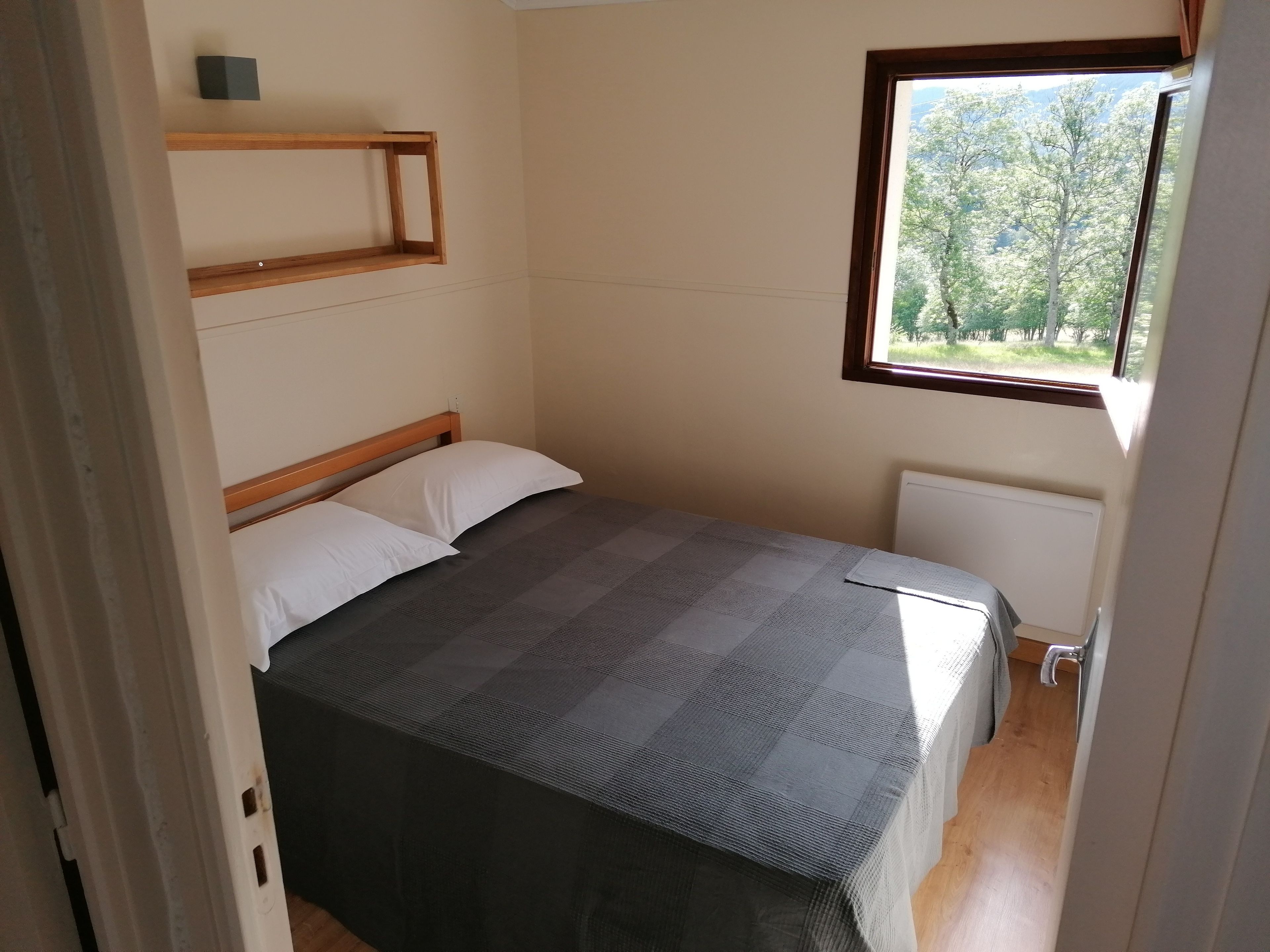 A small, simple room with a bed, a window, and a radiator.