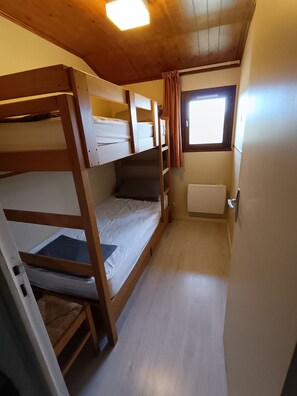 Dormitorio con literas, ventana y radiador.