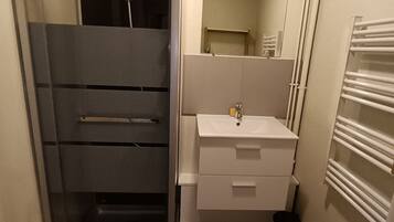 Ein Badezimmer mit Duschkabine, Waschbecken, Spiegel und Toilette.