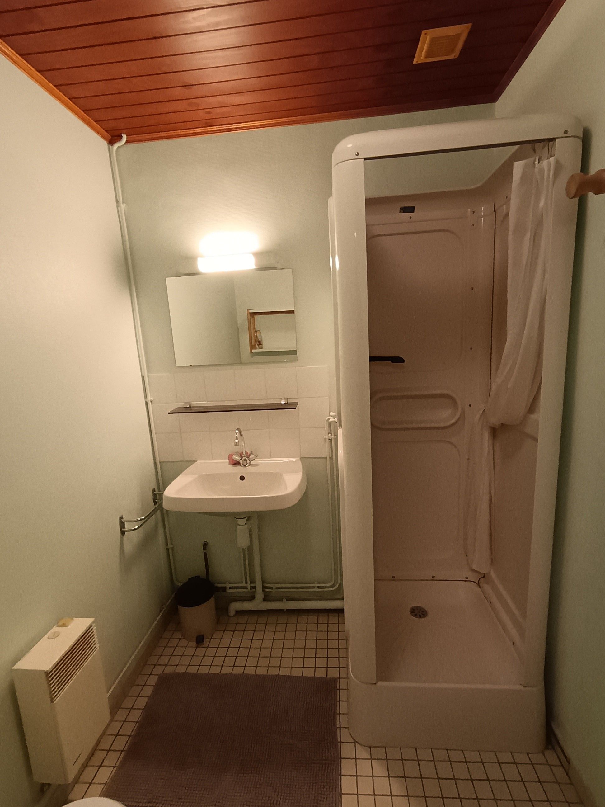 A bathroom with a white sink, mirror, and shower enclosure.