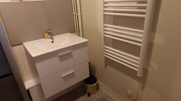 A bathroom with a white sink, a mirror, a towel rack, and a toilet.