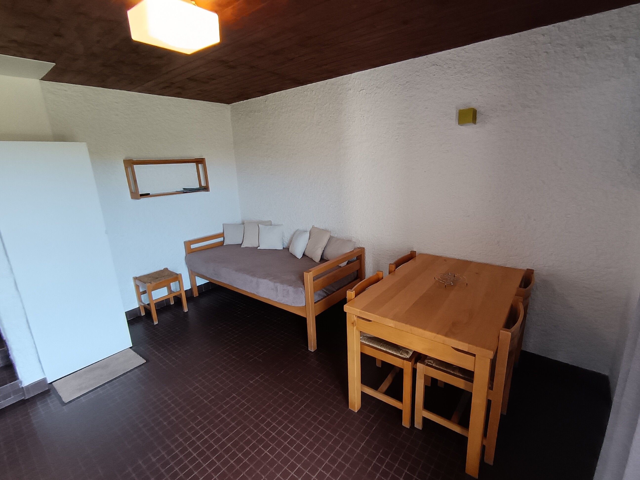 A room with a wooden bed, a small table, and a larger dining table.