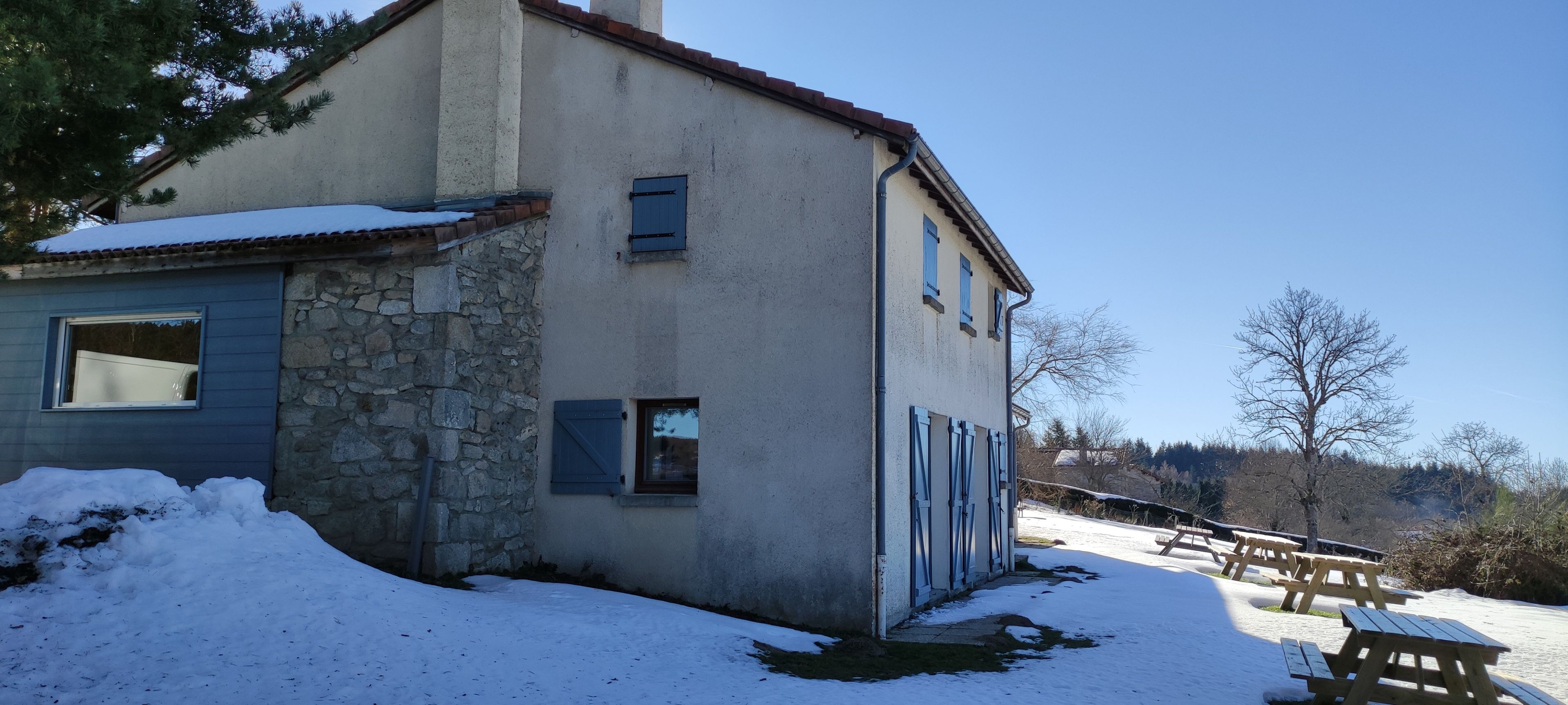A two-story house with a stone facade and a blue window.
