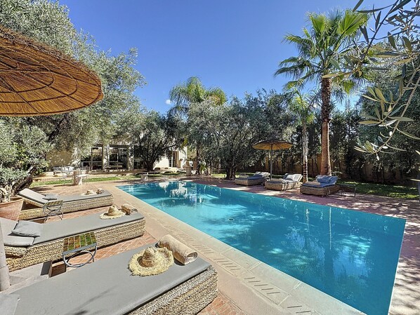 A swimming pool with lounge chairs and umbrellas, surrounded by trees and a building. - ZALUNA Marrakech Private Villa & Heated Pool (Sidi Bouzguia)