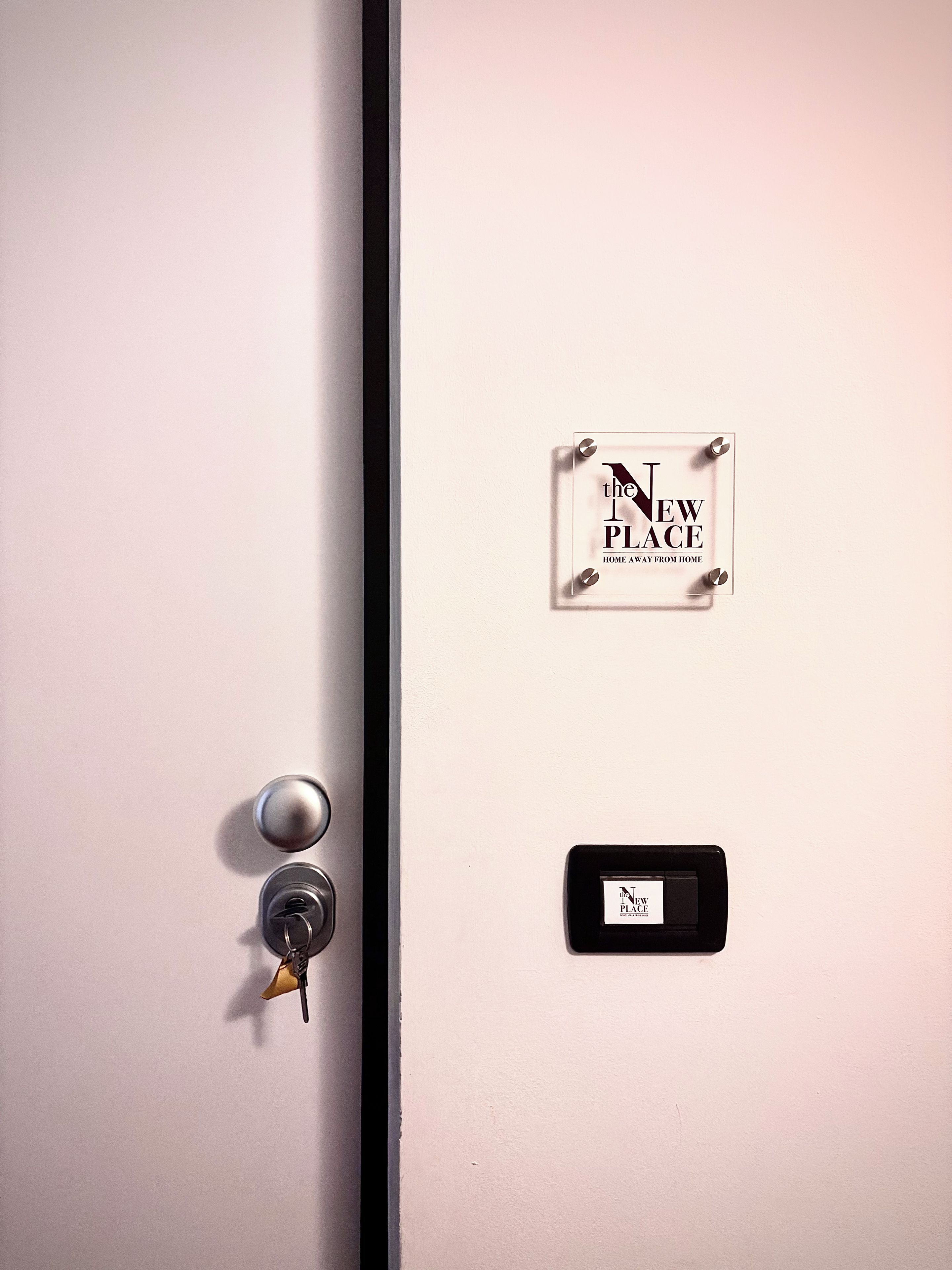 A door with a keyhole, a lock, and a sign that reads 'THE NEW PLACE HOME AWAY FROM HOME'.
