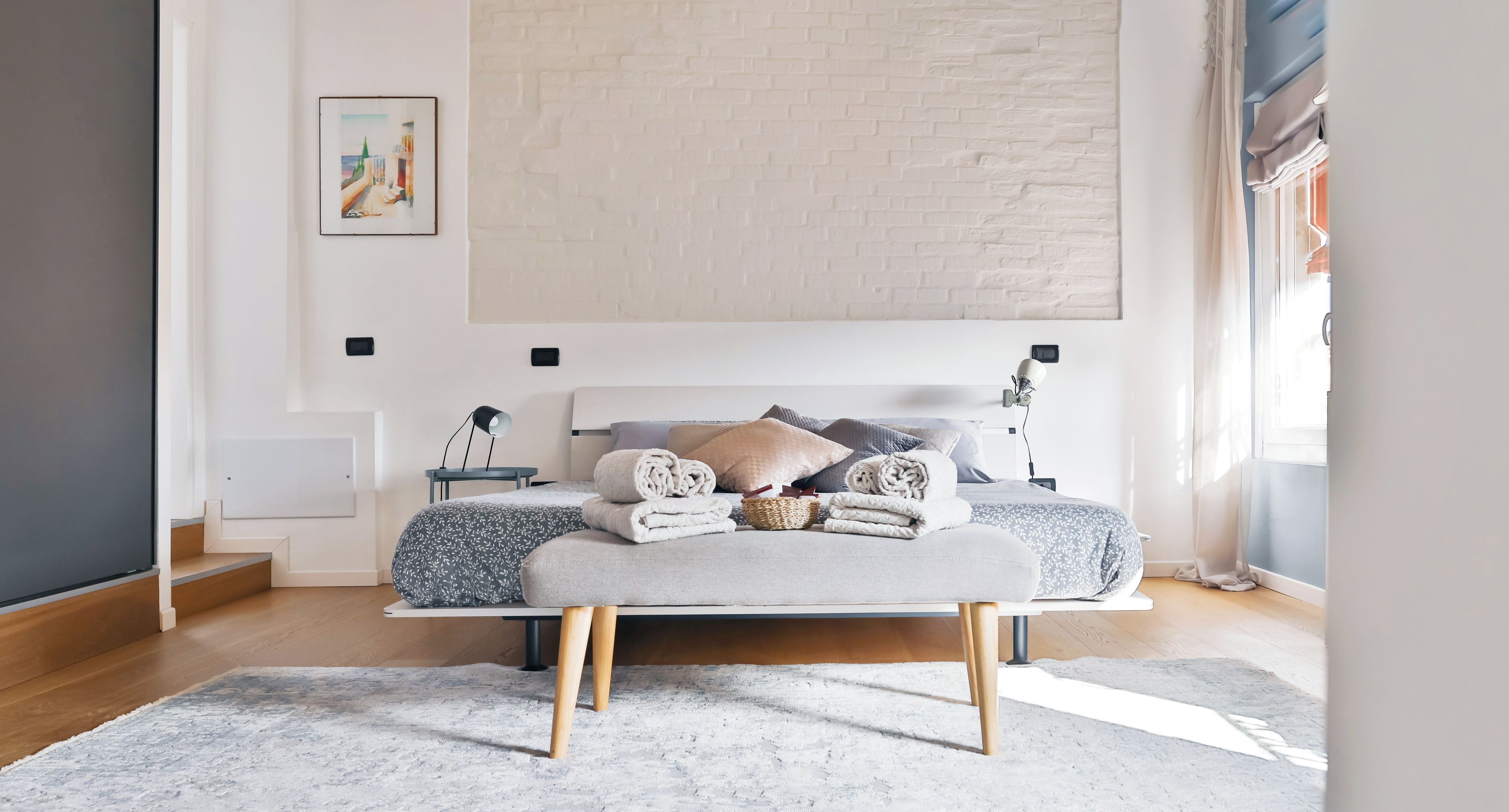 Quarto moderno com cama, mesas de cabeceira e uma janela grande.