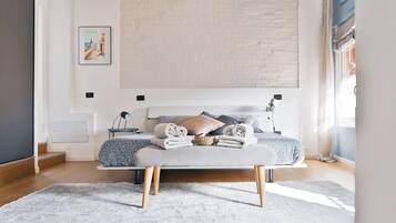 Quarto moderno com cama, mesas de cabeceira e uma janela grande.