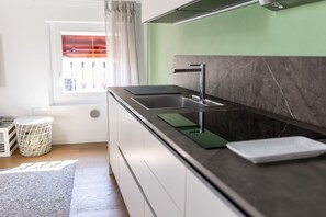 Eine moderne Küche mit schwarzem Arbeitsplatz, einer Edelstahl-Spüle und einer grünen Spritzschutzwand.