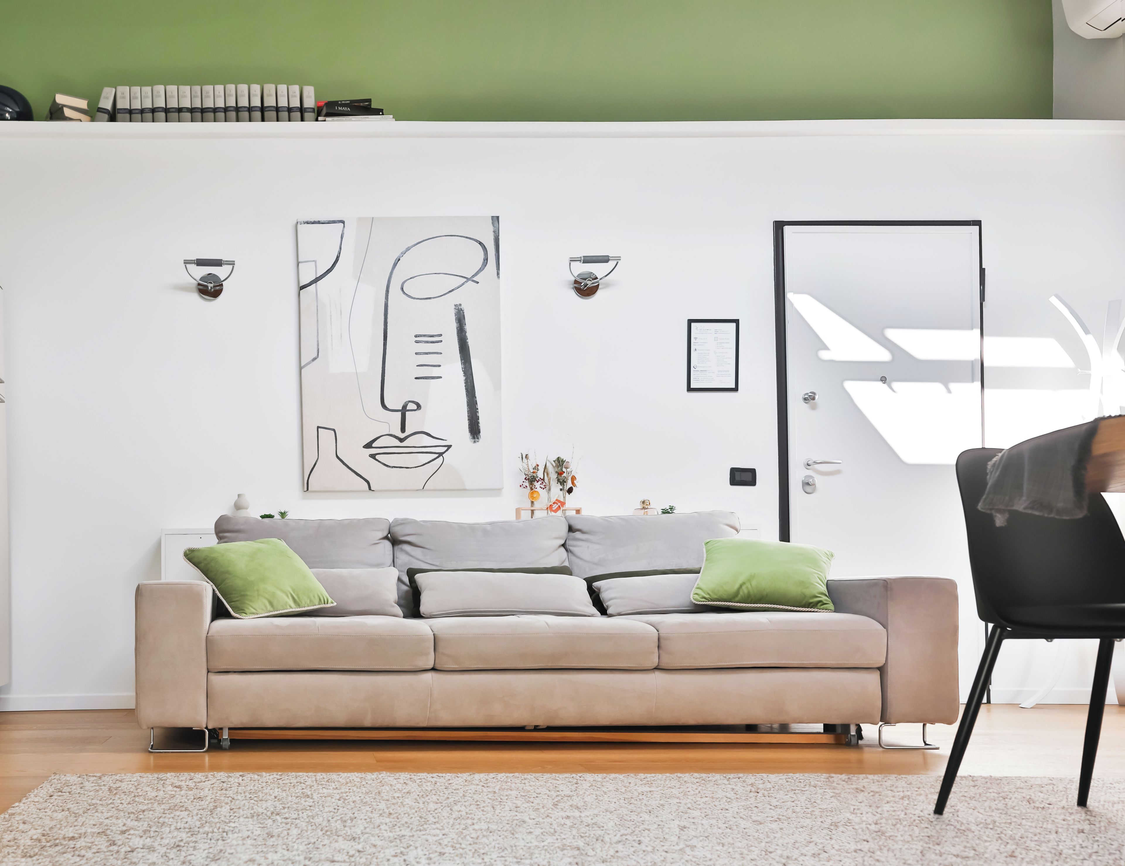 Uma sala de estar moderna com um sofá, uma porta e uma obra de arte abstrata fixada na parede.