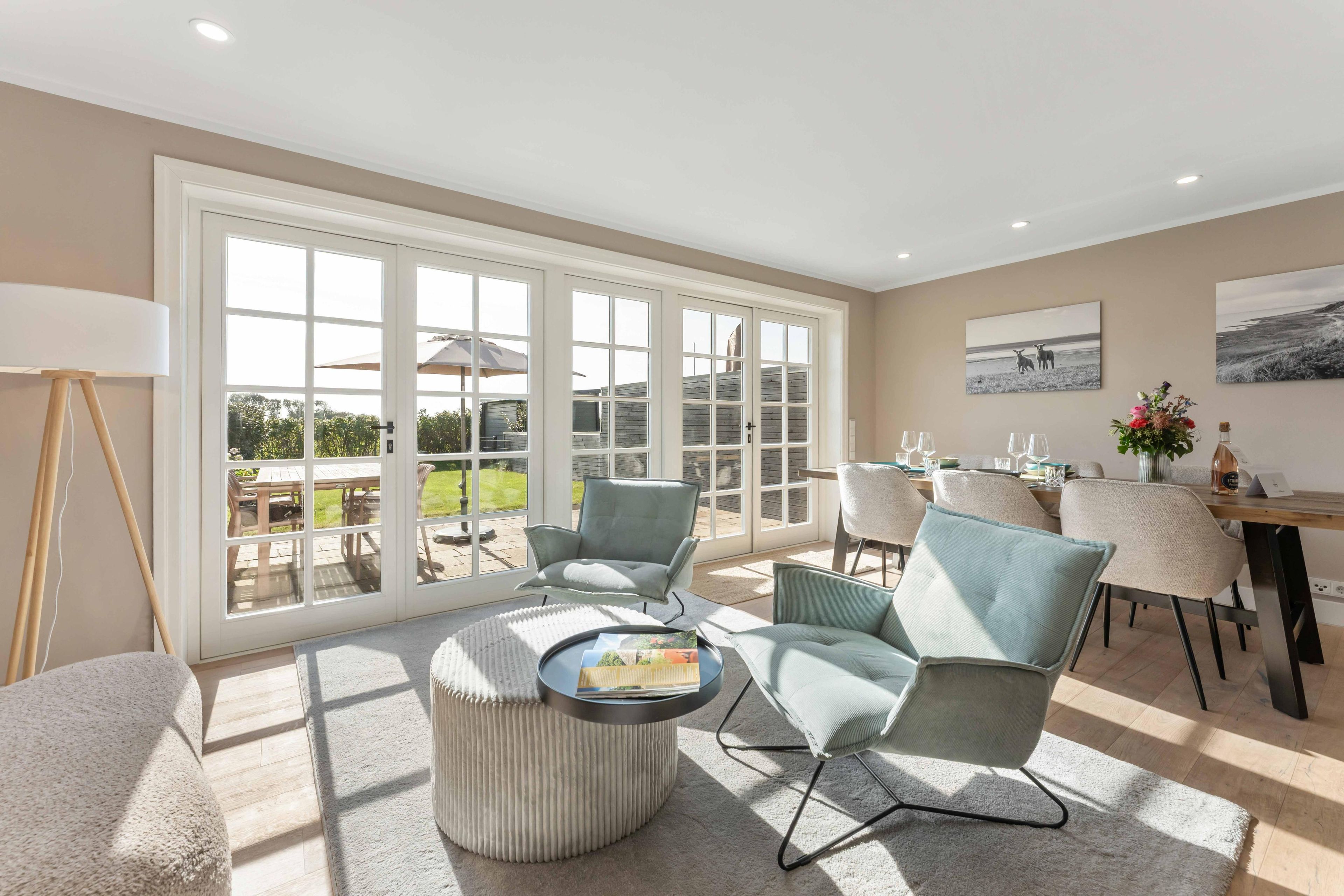 A spacious room with large windows, a dining area, and a seating arrangement.