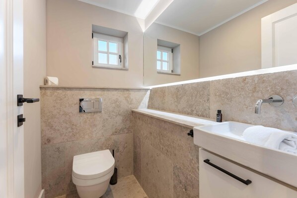 Une salle de bain comprenant des toilettes, un lavabo et un espace douche.
