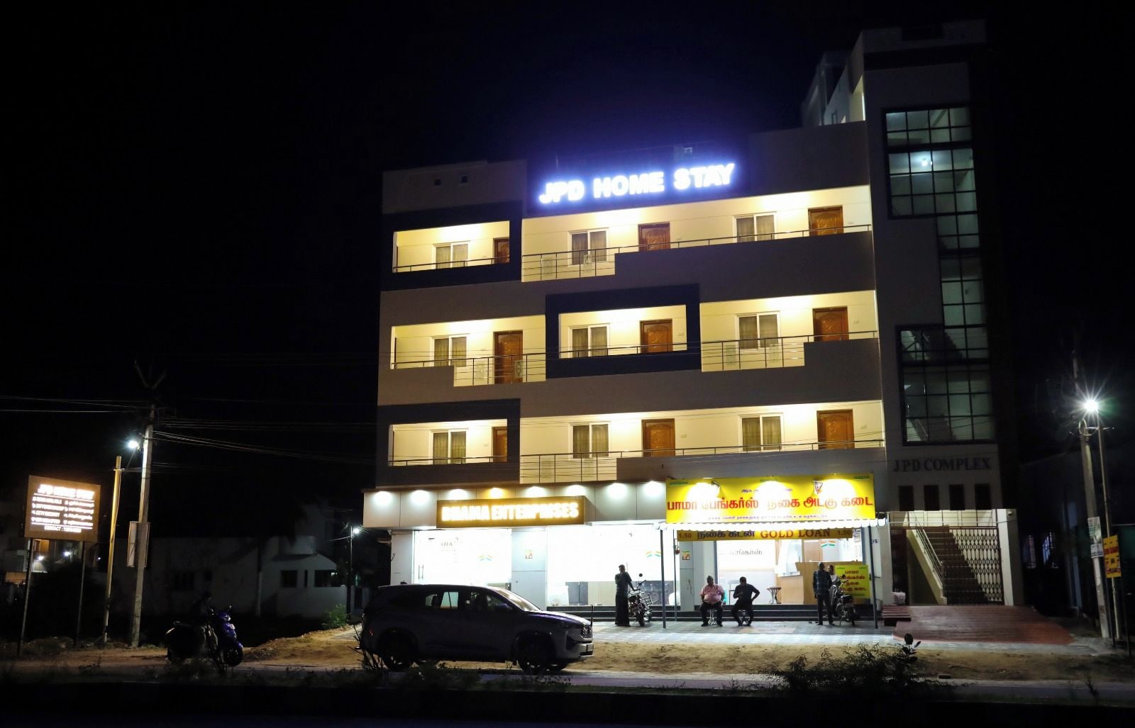 A multi-story building with a sign for 'JPD HOME STAY' and 'BRAND ENTERPRISES' at the ground level.