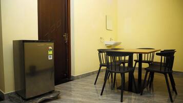 A compact room with a refrigerator, a sink, and a dining table with chairs.