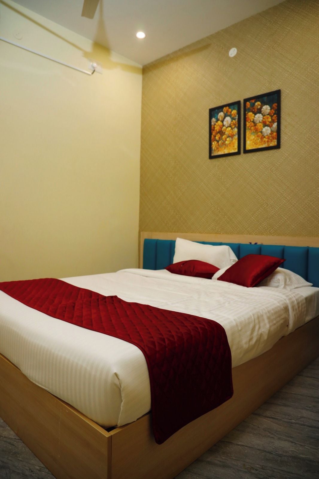 A hotel room with a bed, a headboard, and two wall-mounted paintings.
