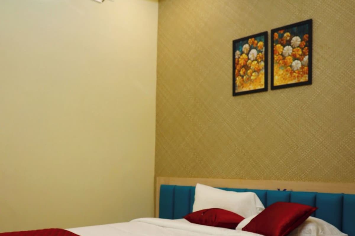Una habitación de hotel con una cama, cabecero y dos cuadros colgados en la pared.