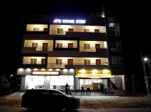 Un edificio de varios pisos con letreros que indican 'JPD HOME STAY' y 'BHAMA ENTERPRISES'.