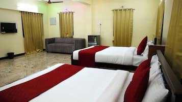 Habitación de hotel con dos camas, un sofá, un televisor y un ventilador de techo.