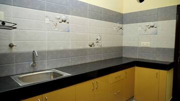 A kitchen with a black countertop, stainless steel sink, and yellow cabinets.