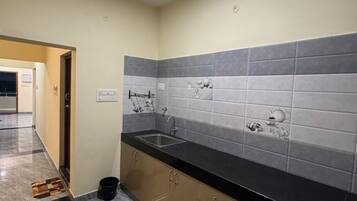 Una cocina moderna con piso de mármol, encimera negra y salpicadero con azulejos grises.