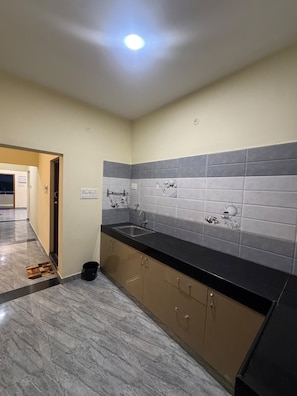 Una cocina moderna con piso de mármol, encimera negra y salpicadero con azulejos grises.