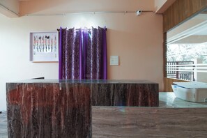 Ein Empfangstresen mit Marmorplatte, violette Vorhänge, ein an der Wand montierter Lichtschalter und eine Überwachungskamera.