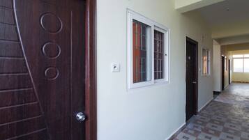 A hallway with a patterned floor, a wooden door with circular designs, and a window with a white frame.