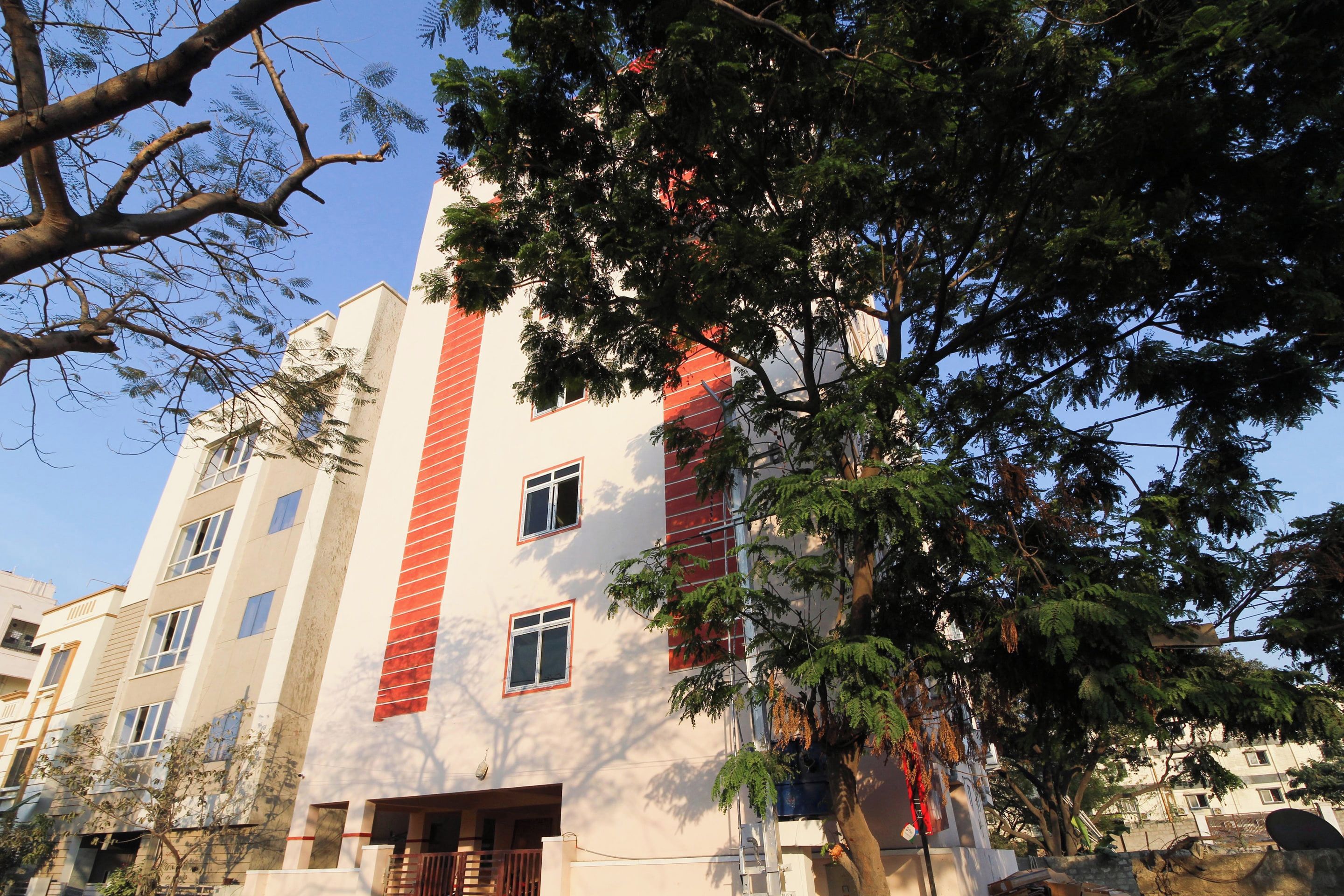 Un edificio de varios pisos con una franja vertical roja, ventanas y un balcón.