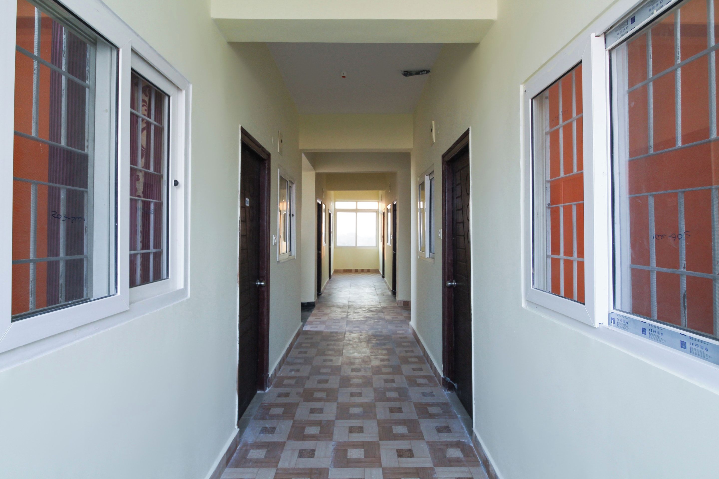 Un pasillo con puertas a ambos lados, que conduce a una habitación luminosa al final.