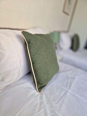 A bed with white bedding and a green pillow with a beige trim. - Cosy 2 Bedroom Home in Great Location (Shenley Lodge)