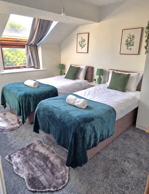 A hotel room with two beds, a large window with curtains, and a view of greenery outside. - Cosy 2 Bedroom Home in Great Location (Shenley Lodge)
