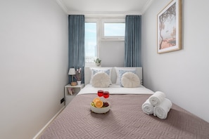 A hotel room with a bed, a bedside table with a lamp, a bowl of fruit, and towels. - Lumina 2room Apart in Center I City View (Warszawa)