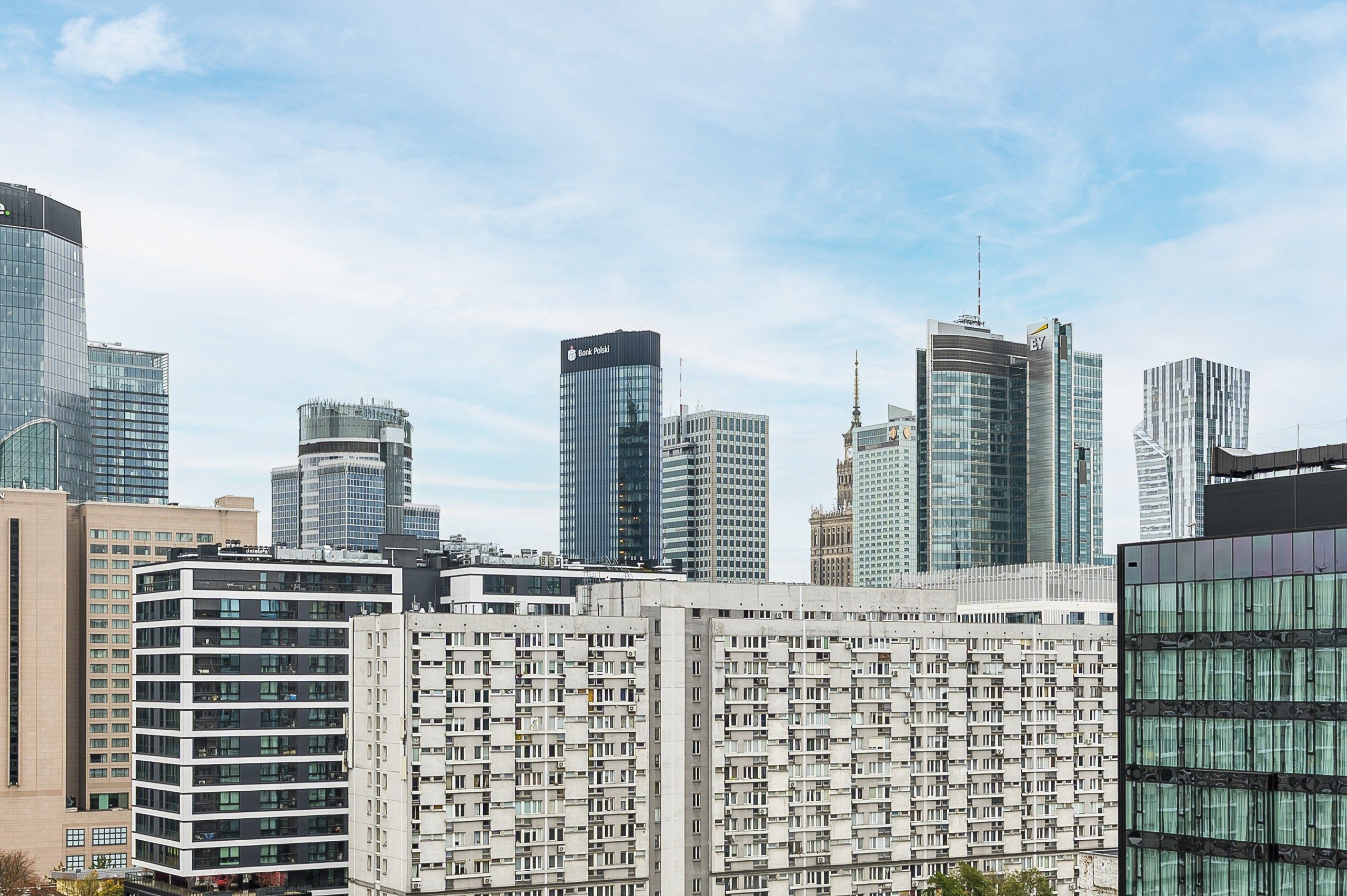 A cityscape with modern high-rise buildings, including a prominent Bank Polski and a building with the EY logo.