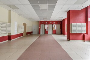 A hallway with lockers on both sides, numbered doors, and a tiled floor. - Lumina 2room Apart in Center I City View (Warszawa)