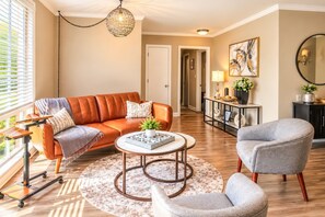 A living room with a leather sofa, a grey armchair, a coffee table, and a floor lamp. - Larry's Love - A Coastal Retreat Near the Beach (Wilmington)