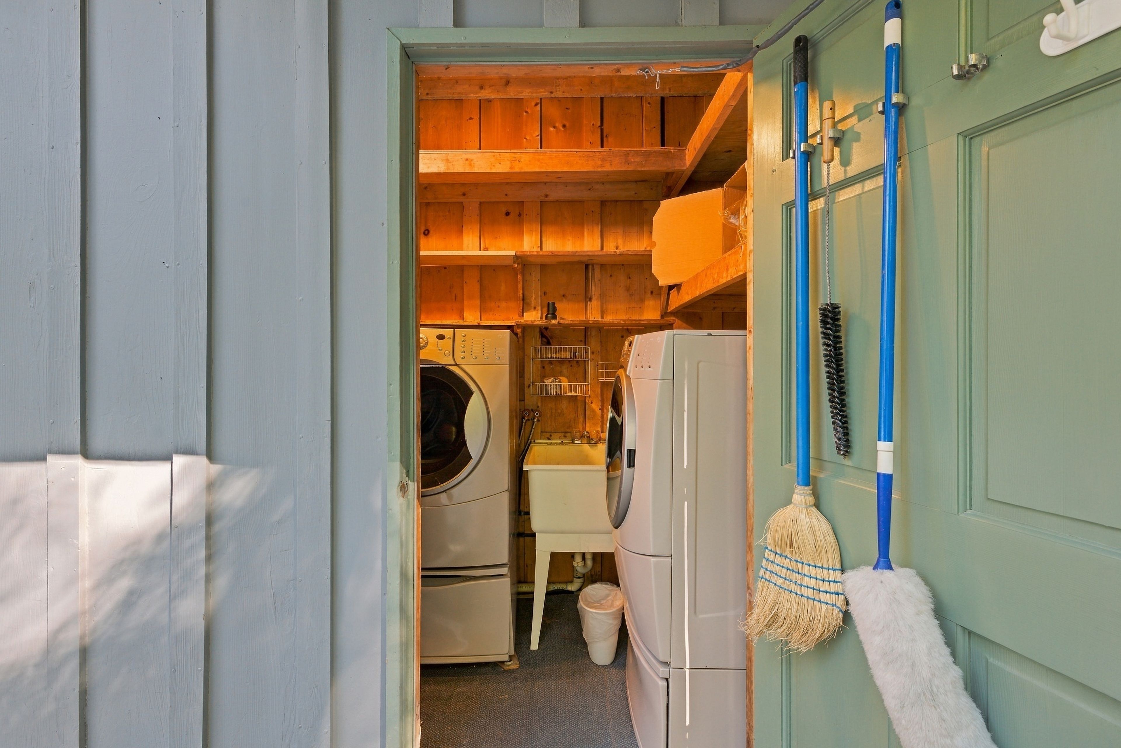 Une buanderie équipée d’un lave-linge, d’un sèche-linge et d’un balai.