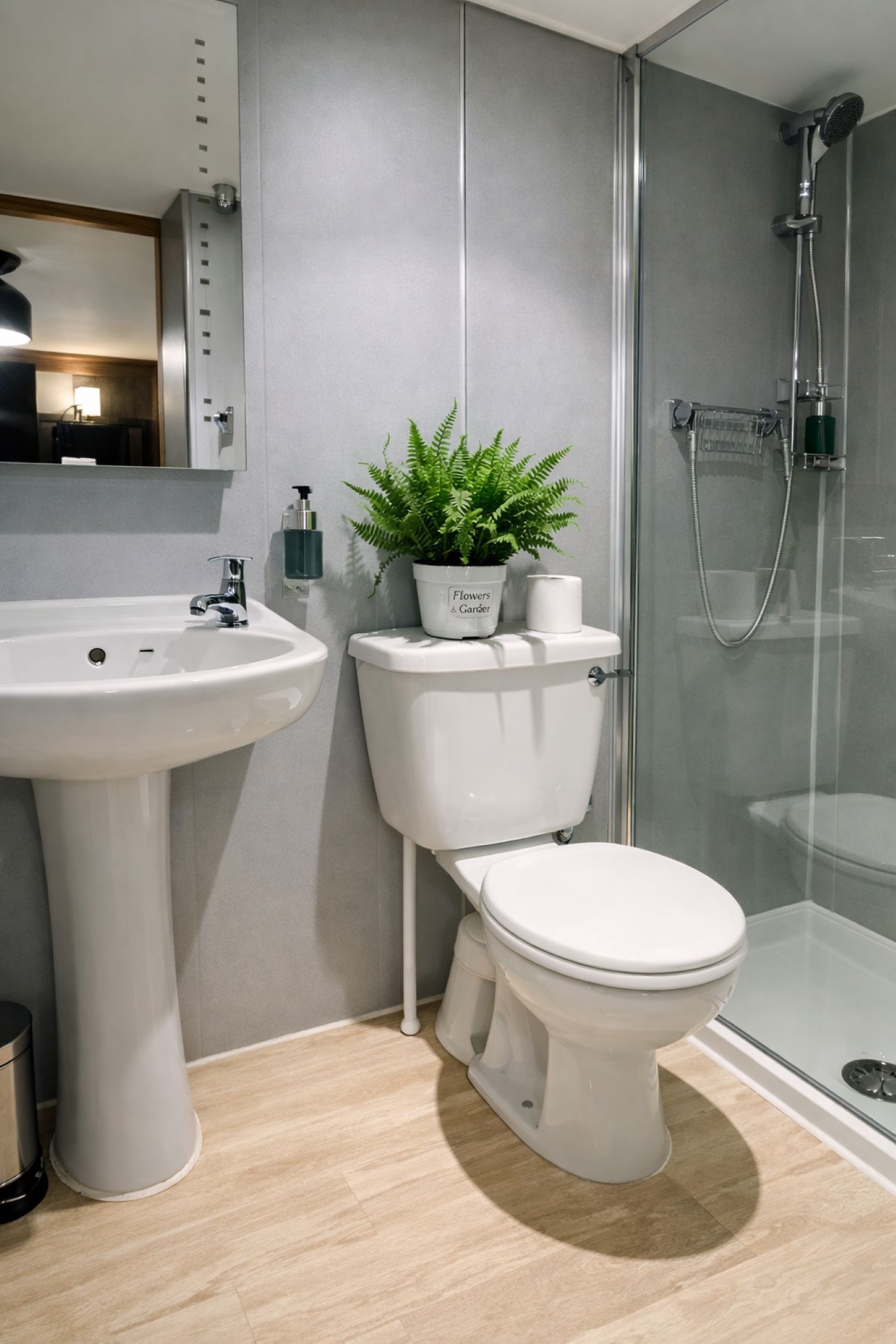 Ein modernes Badezimmer mit einem Waschbecken auf Säule, Toilette und einer Duschkabine.