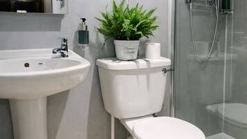 Ein modernes Badezimmer mit einem Waschbecken auf Säule, Toilette und einer Duschkabine.
