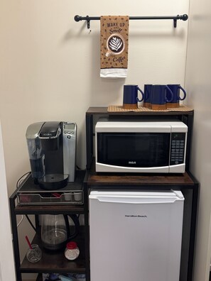 Una kitchenette equipada con una cafetera Keurig, un microondas y un mini refrigerador Hamilton Beach.