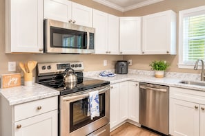 Una cocina moderna con armarios blancos, electrodomésticos de acero inoxidable y encimera de mármol.
