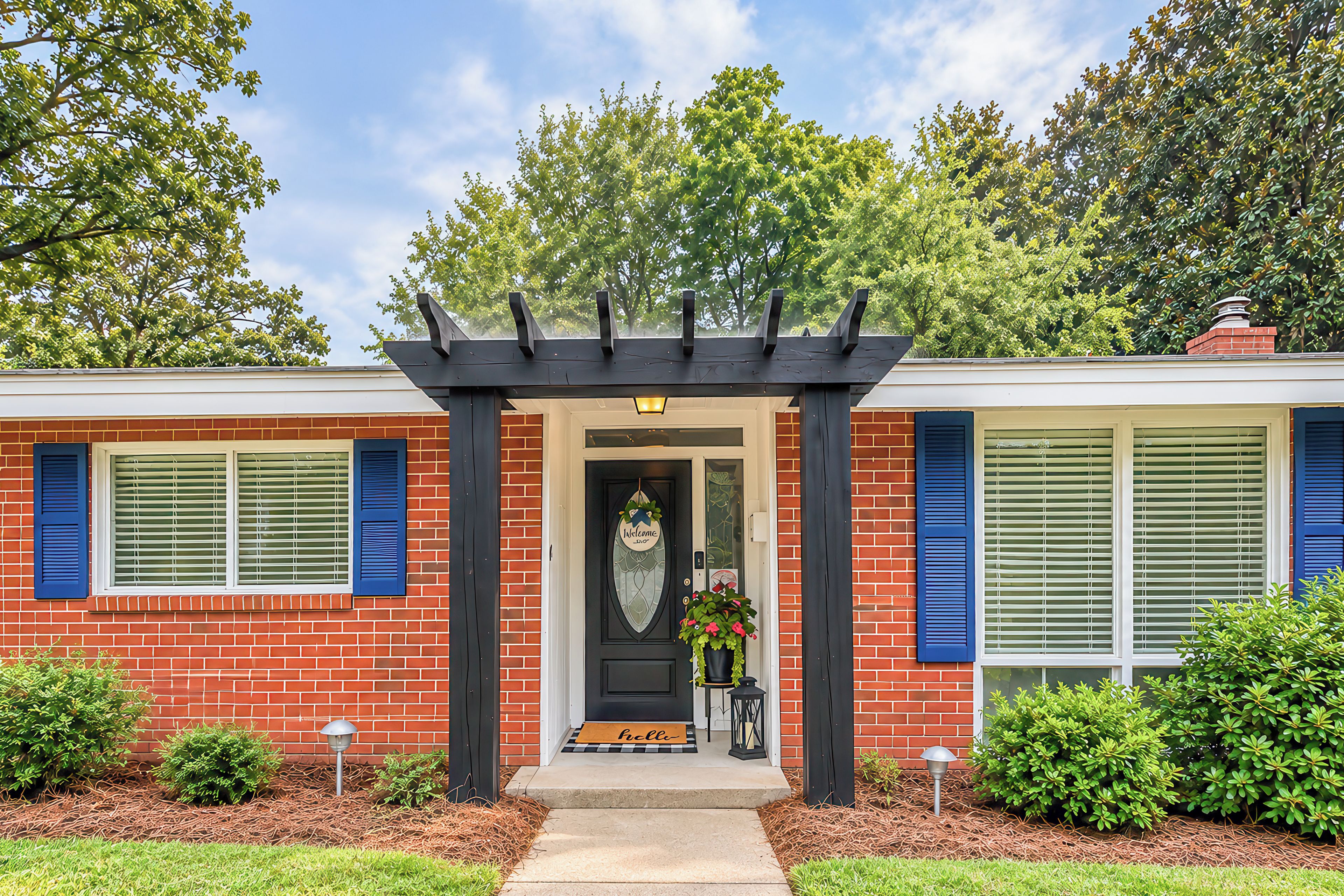 A two-story house with a front porch, a welcome mat, and a potted plant.