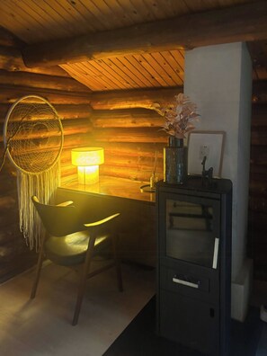 A cozy cabin interior with a wooden ceiling, a desk with a lamp, a chair, and a cabinet. - Timber-framed house with sedum roof in nature (Frederiksværk)