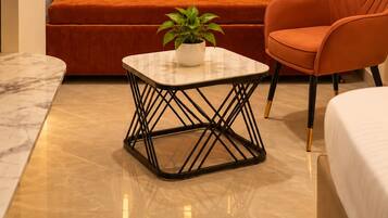 Una sala de estar moderna con un sofá, una mesa de centro y una silla. Hay una planta sobre la mesa de centro.