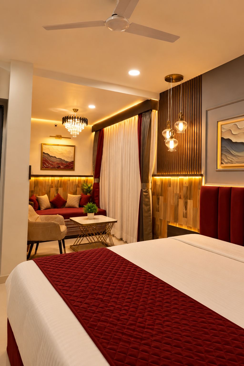 Una habitación de hotel con cama, una zona de estar con mesa y un ventilador de techo.