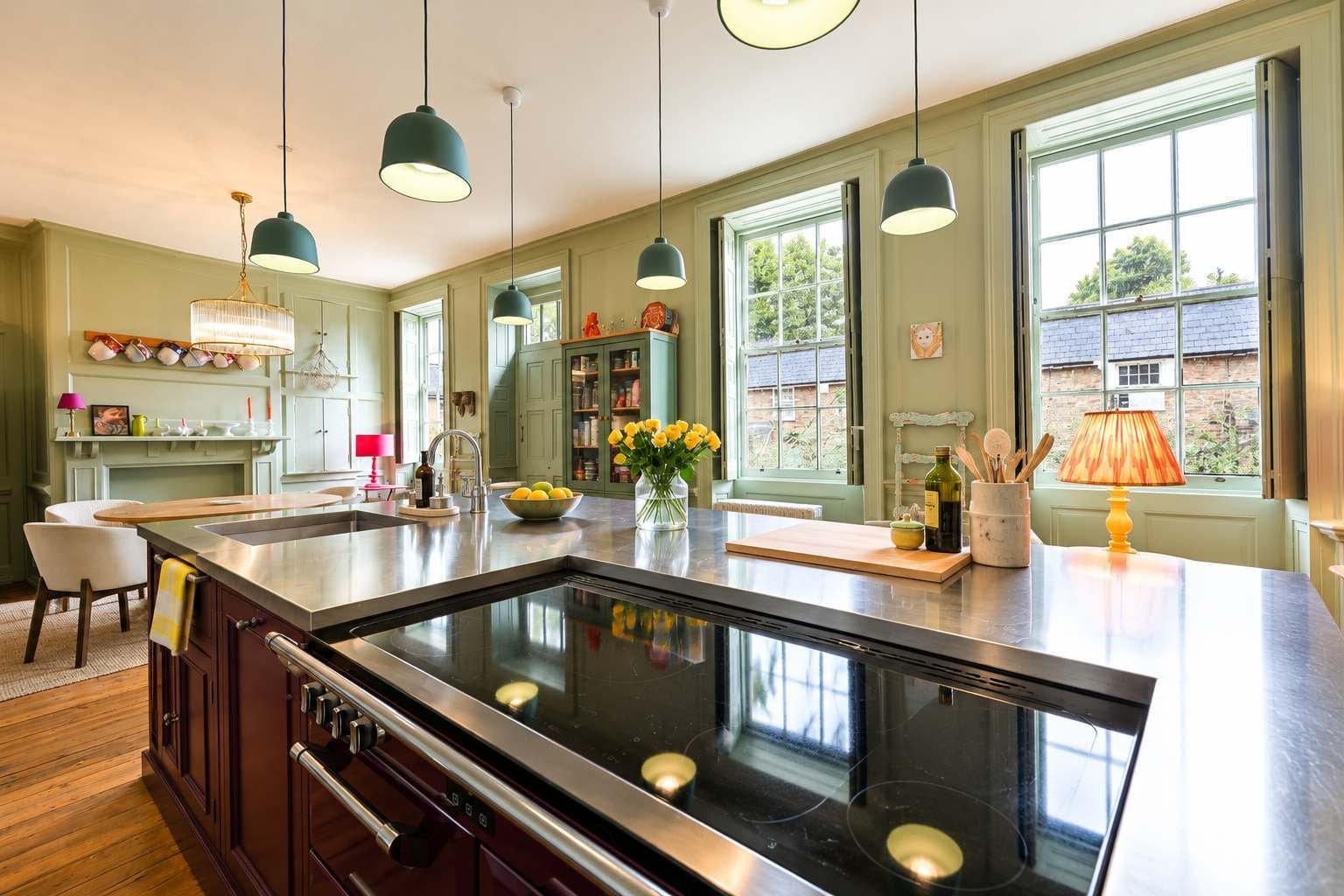 A modern kitchen with a central island, pendant lighting, and large windows.