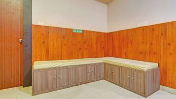 A corner room with a built-in bench, a door, and a fire exit sign.