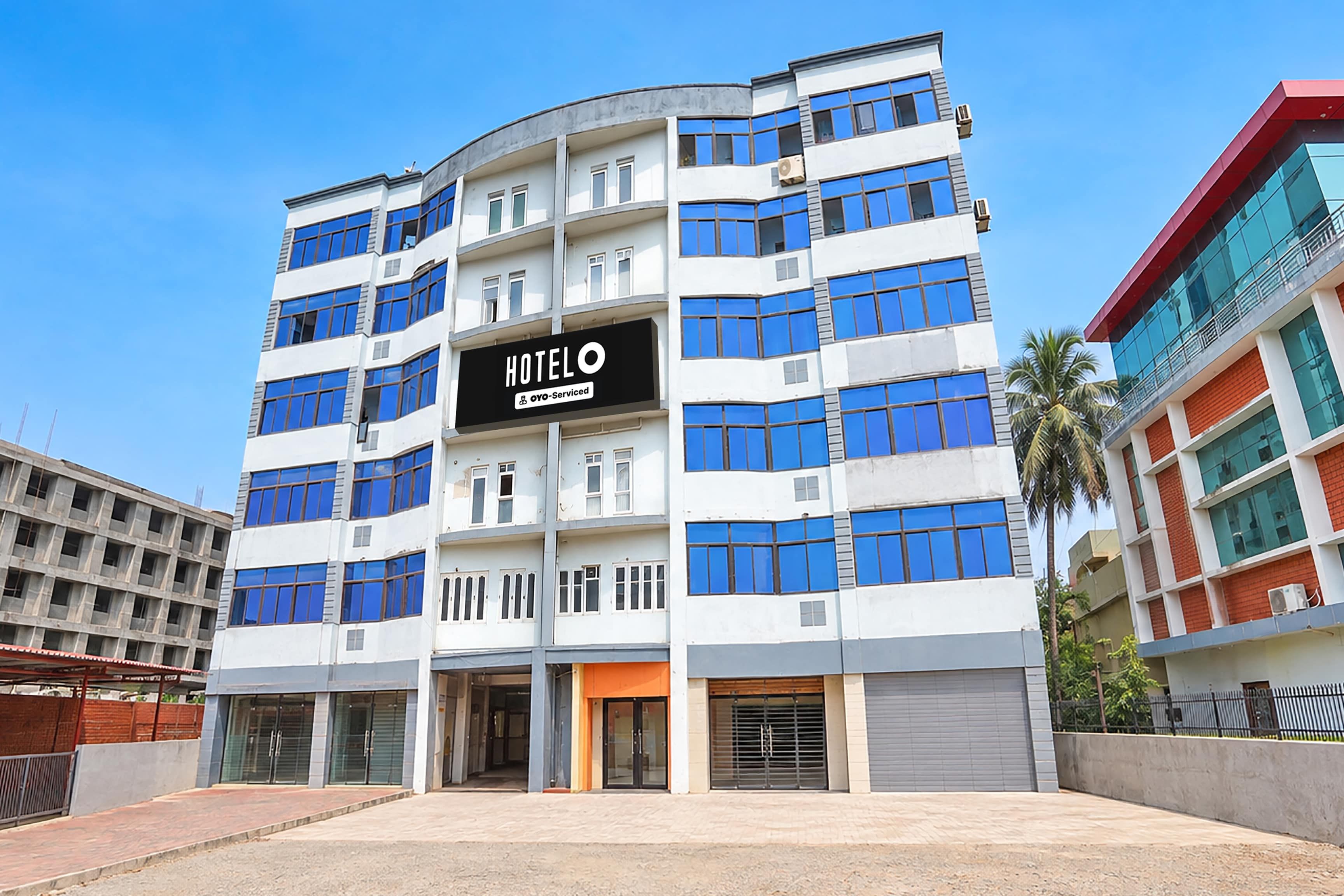 A multi-story hotel building with a prominent 'HOTEL O' sign, featuring a modern architectural design with blue-tinted windows and a flat roof.