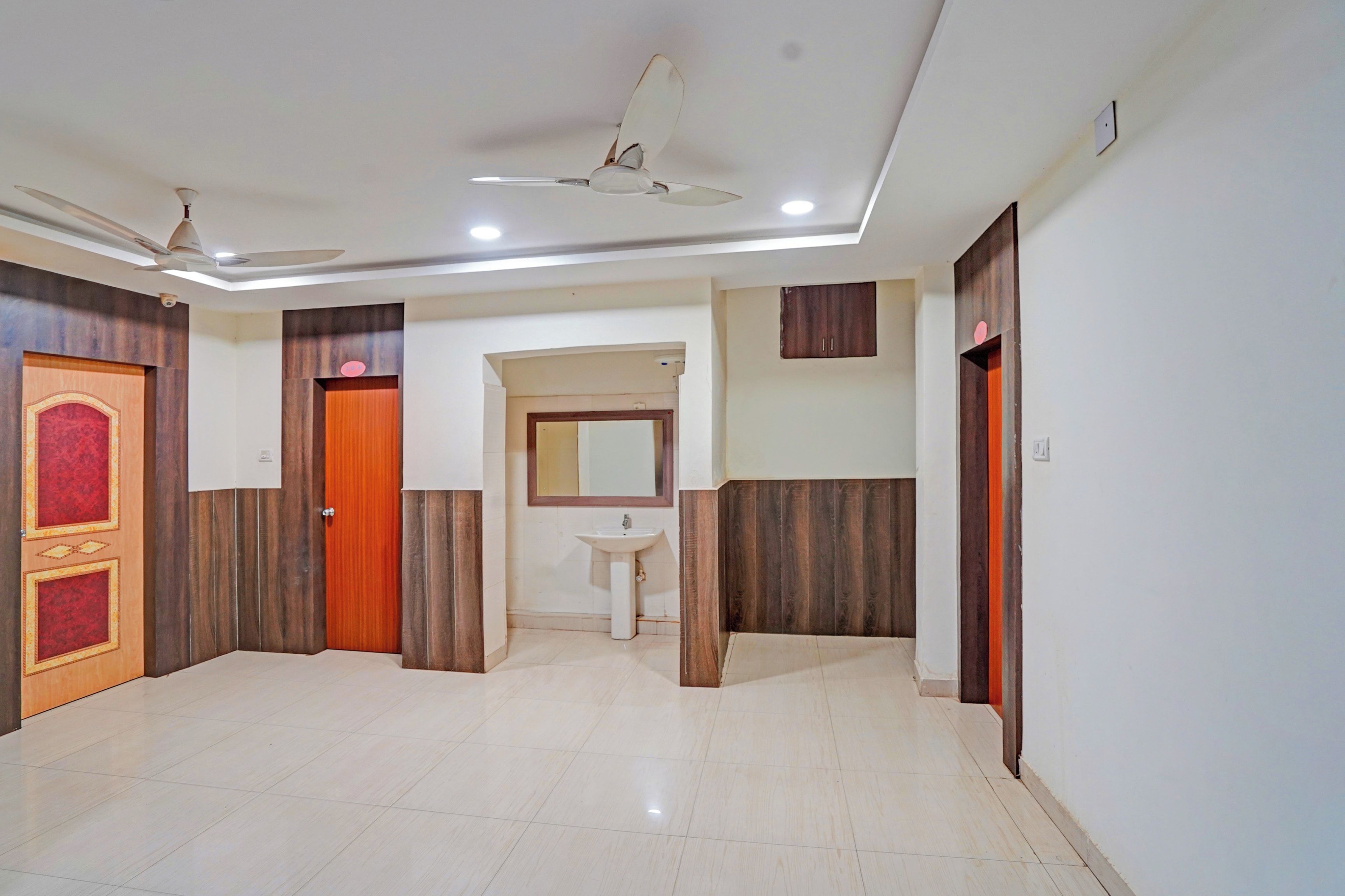 A hotel room with a tiled floor, a ceiling fan, a sink, and wooden paneling on the walls.