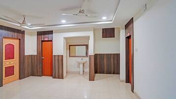 A hotel room with a tiled floor, a ceiling fan, a sink, and wooden paneling on the walls.