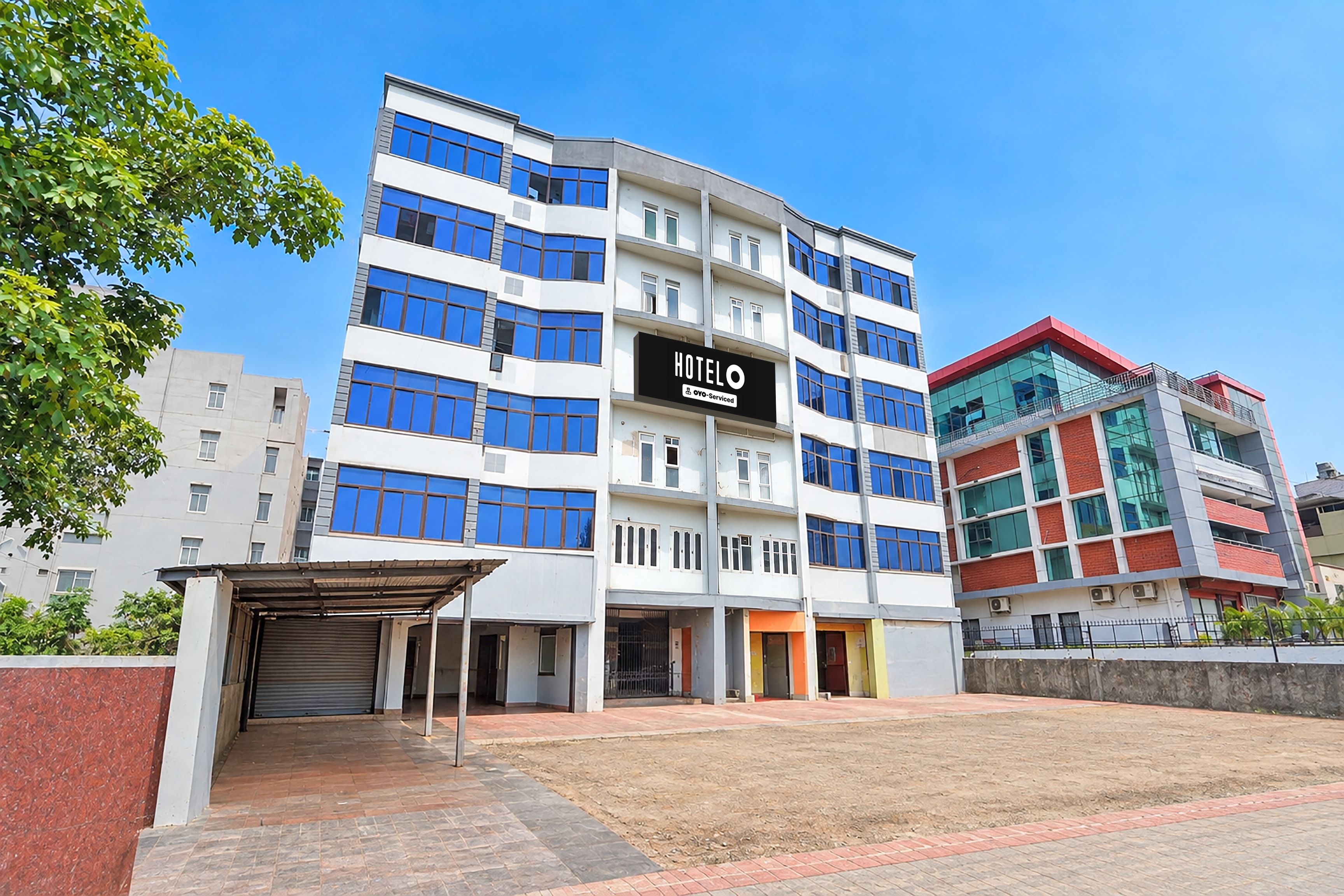 A multi-story hotel with a prominent 'HOTEL' sign, a covered entrance, and a parking area.